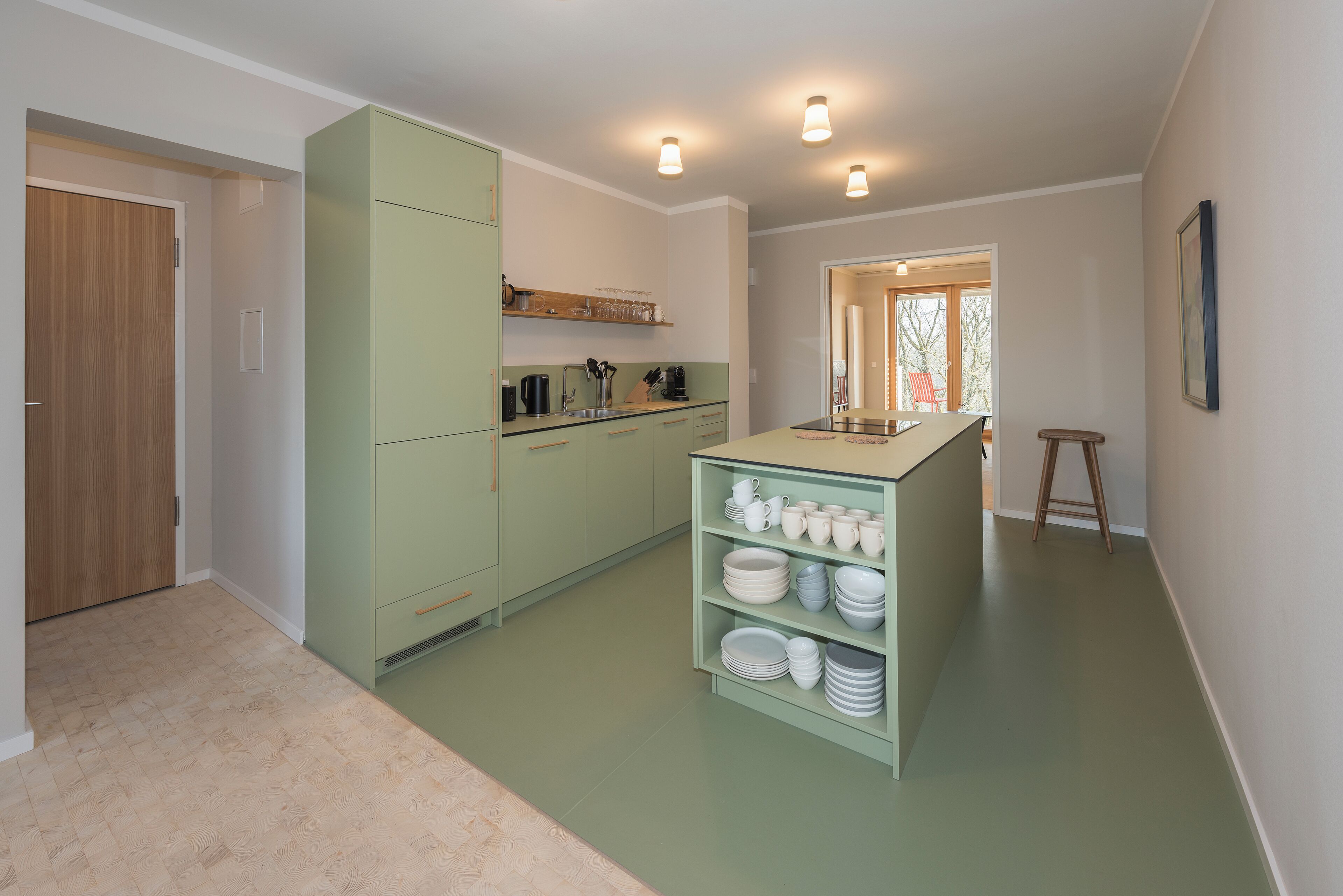 A kitchen with green cabinets, a countertop with dishes, and a wooden door.