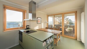 A modern kitchen with a dining area, large windows, and a view of the outdoors. - SEEZIEGE Ferienwohungen in der Uckermark (Boitzenburger Land)