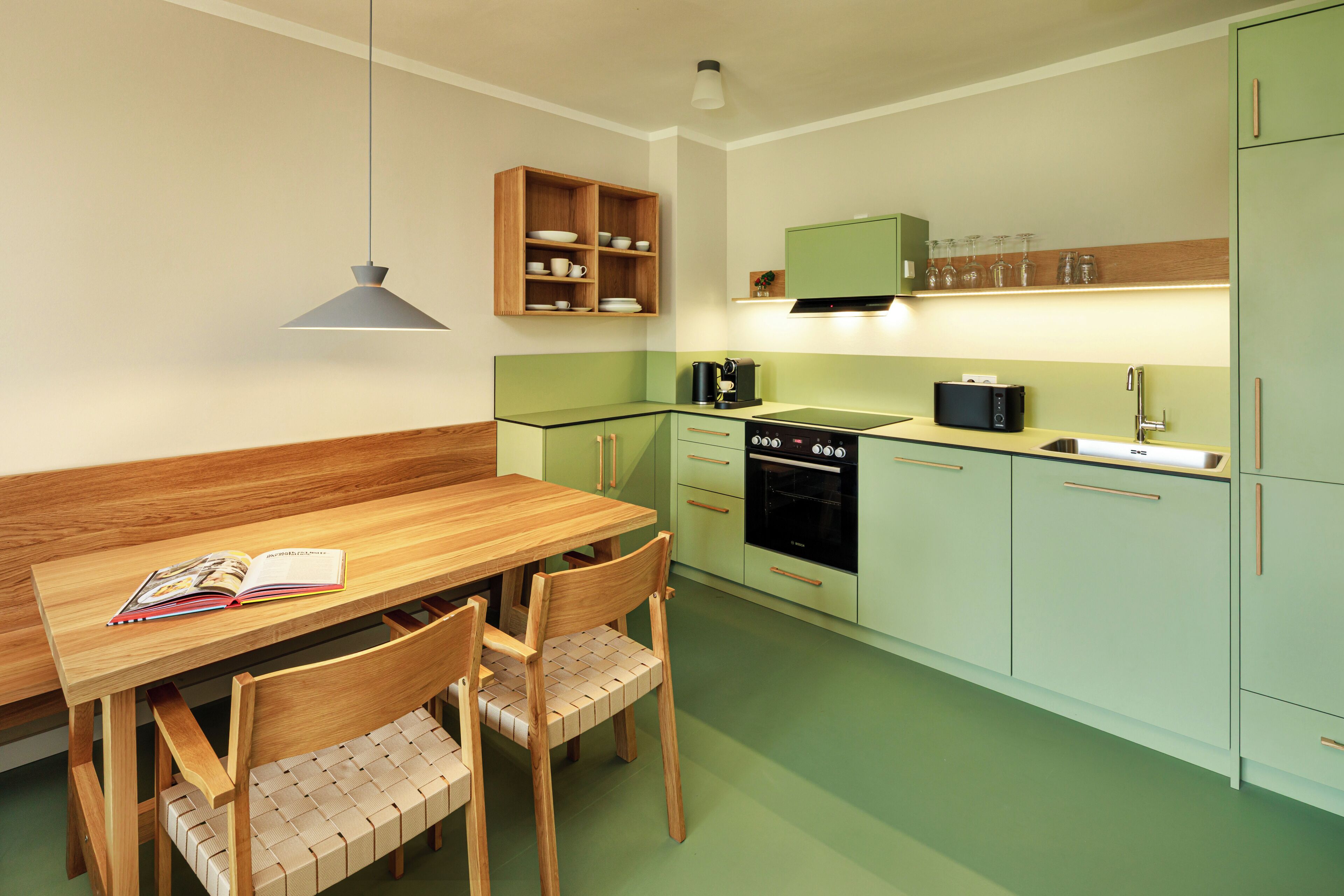 A compact kitchen with a dining table, chairs, a built-in oven, and a microwave.