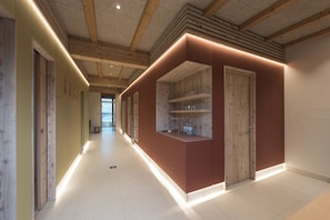 A hallway with wooden beams, a built-in kitchen area with a sink and shelves, and a view to the outside. - SEEZIEGE Ferienwohungen in der Uckermark (Boitzenburger Land)