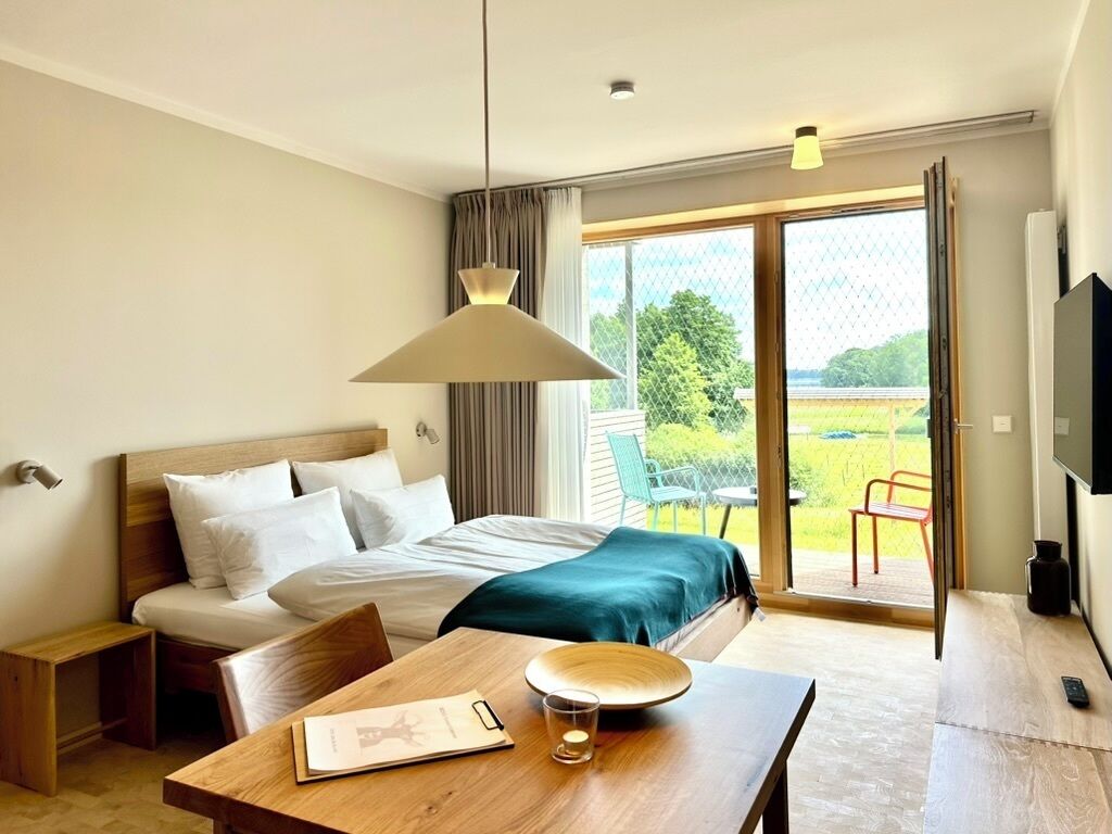 Habitación de hotel con cama, una mesa de madera, un televisor y vistas al exterior.
