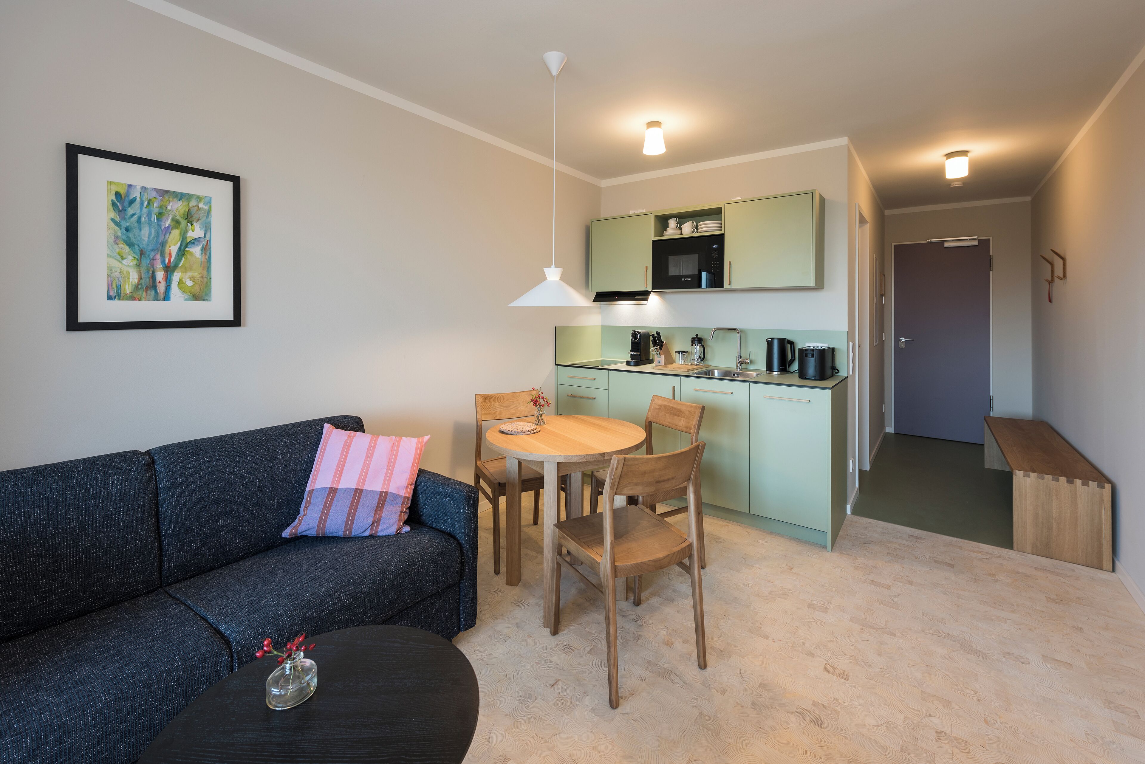 Un espacio habitable compacto con sofá, mesa de comedor y kitchenette.