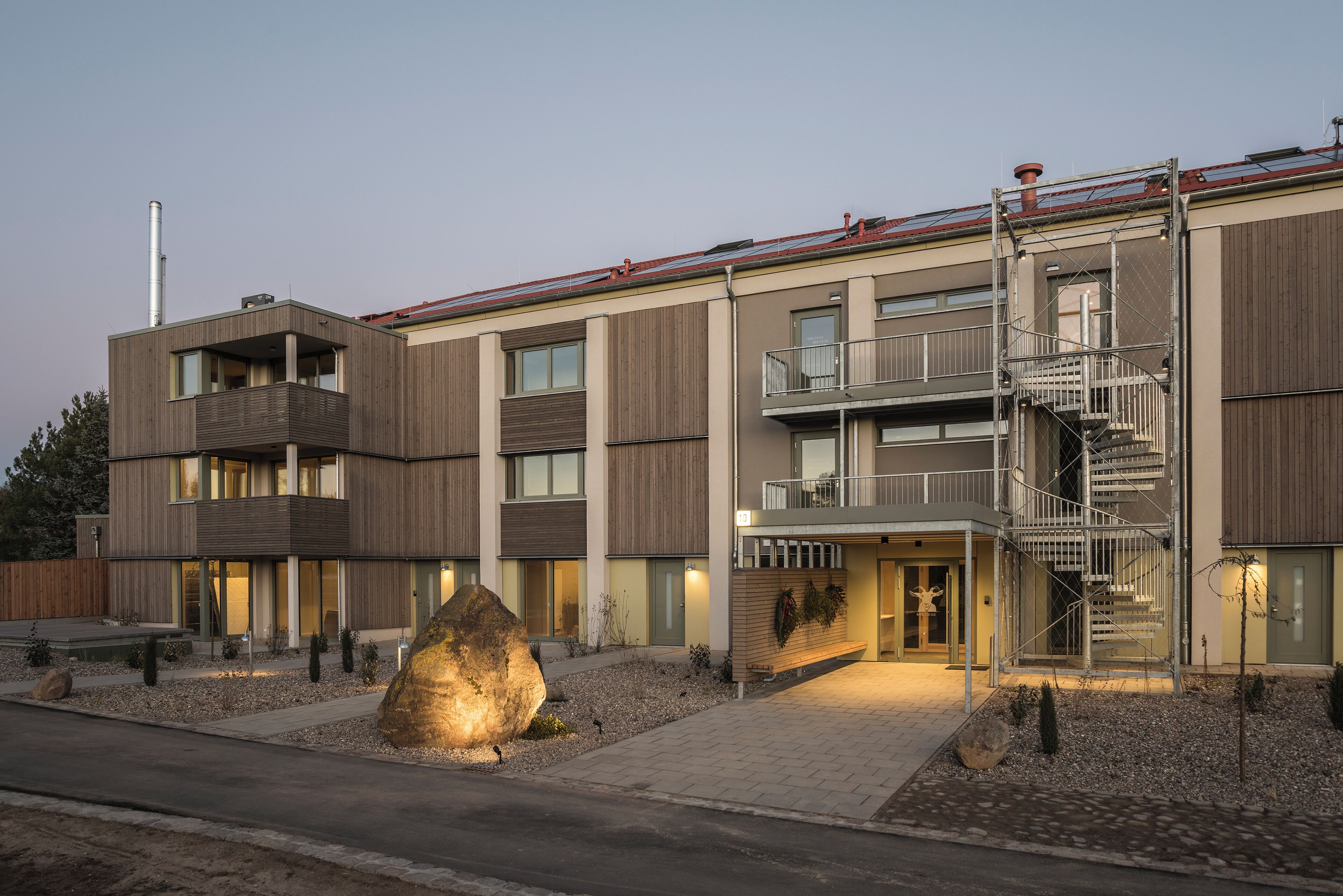 Un edificio moderno de varios pisos con balcones, una entrada central y una escalera.