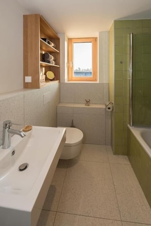 A bathroom with a sink, toilet, and shower. There is a window above the toilet and a shelf with toiletries. - SEEZIEGE Ferienwohungen in der Uckermark (Boitzenburger Land)