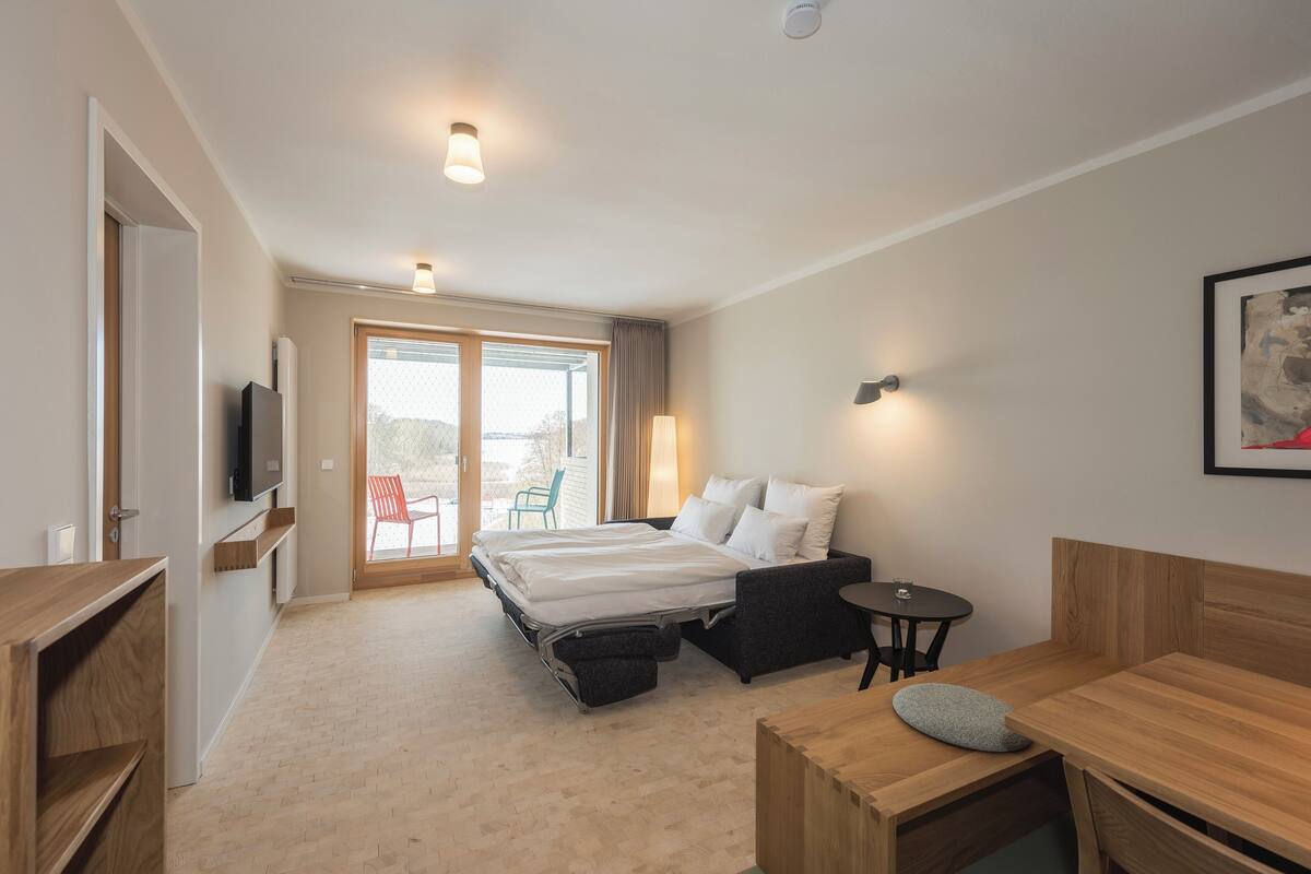 Une chambre d’hôtel moderne équipée d’un lit, d’un bureau, d’une chaise, d’une télévision et offrant une vue sur l’extérieur.