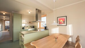 A modern kitchen with a central island, a dining table, and a bench. - SEEZIEGE Ferienwohungen in der Uckermark (Boitzenburger Land)