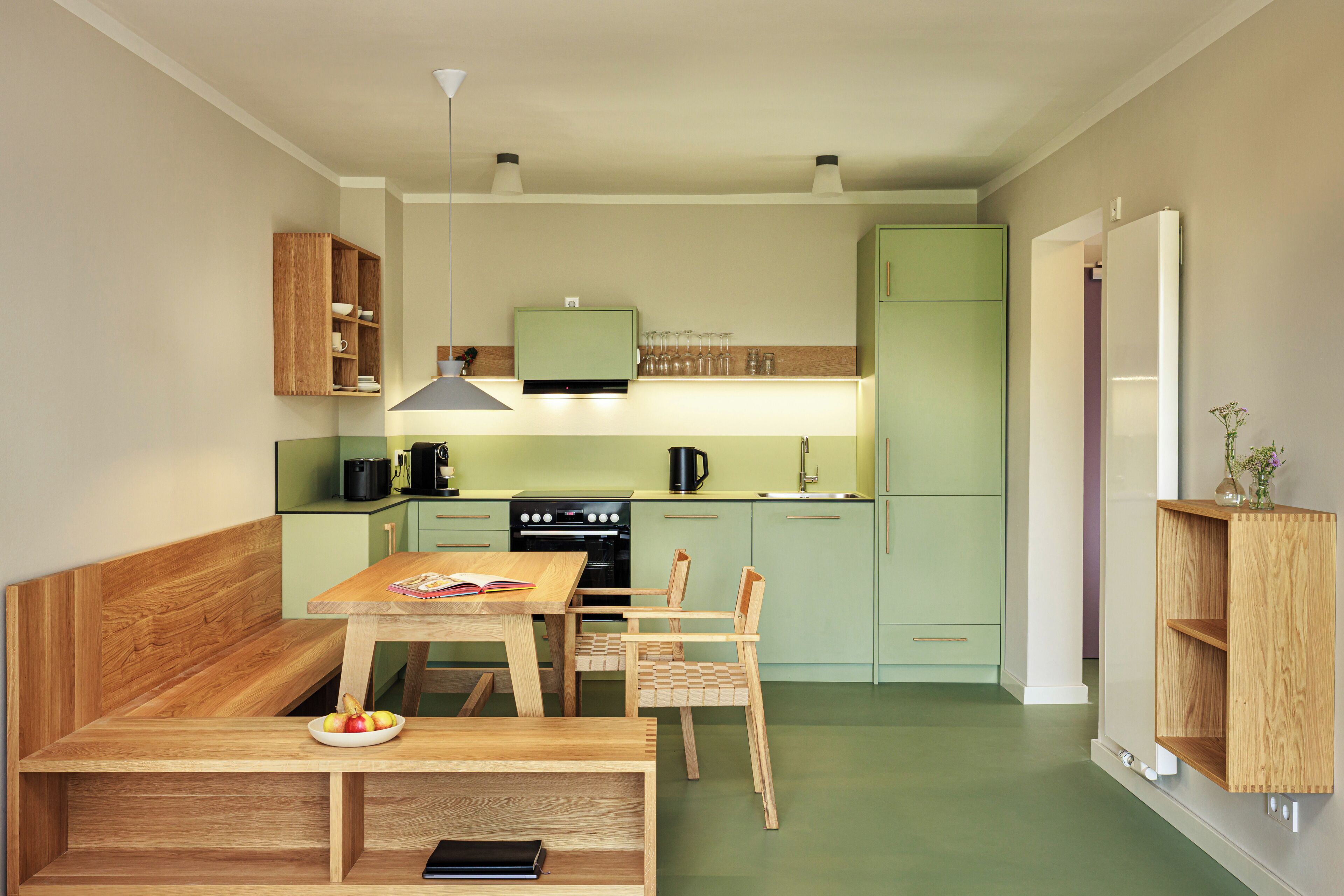 Una cucina compatta con un tavolo da pranzo, sedie, una panca e una libreria a muro.