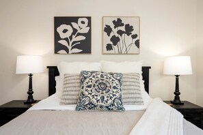 A neatly made bed with a patterned pillow, two bedside lamps, and two framed floral artworks on the wall. - Spacious Modern Cabin on Toledo Bend Lake with Gorgeous Deck and Patio for an Amazing Family Getaway in Hemphill, Texas (Hemphill)