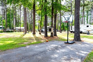 Basketbalveld met een ring, omringd door bomen en campers.