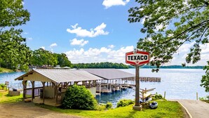Ein an einem See vertäutes Boot, ein überdachtes Pavillon und ein Texaco-Schild.