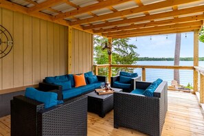 Een overdekt terras met rieten meubilair en uitzicht op een meer.