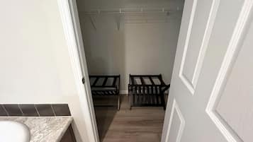 A narrow hallway with a bathroom on the left, a door on the right, and two wooden benches in the center.