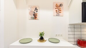 A white countertop with two green plates, a small potted plant, and two abstract wall art pieces. - (MDV120) Study in Carabanchel, Madrid (Madrid)