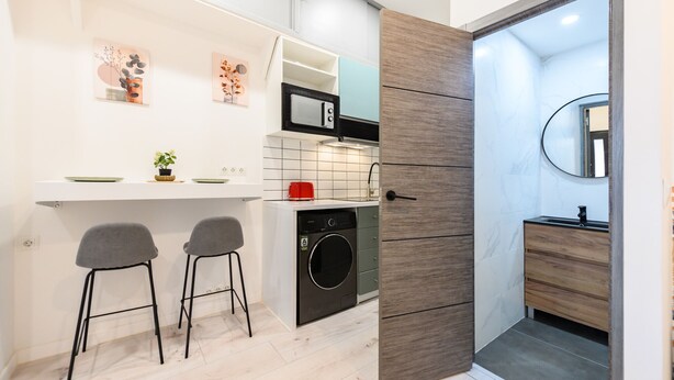 A compact kitchen with a microwave, sink, and washing machine, and a small bar stool. - (MDV120) Study in Carabanchel, Madrid (Madrid)