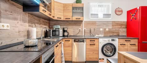 Une cuisine moderne avec des meubles en bois, un lave-vaisselle, une machine à laver et un réfrigérateur rouge.