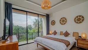 A bedroom with a large bed, a desk, a TV, and a balcony with a view of greenery. - Santara by Prime Villas (Ubud)