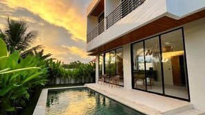 A modern two-story house with a swimming pool, large windows, and a balcony. - Santara by Prime Villas (Ubud)