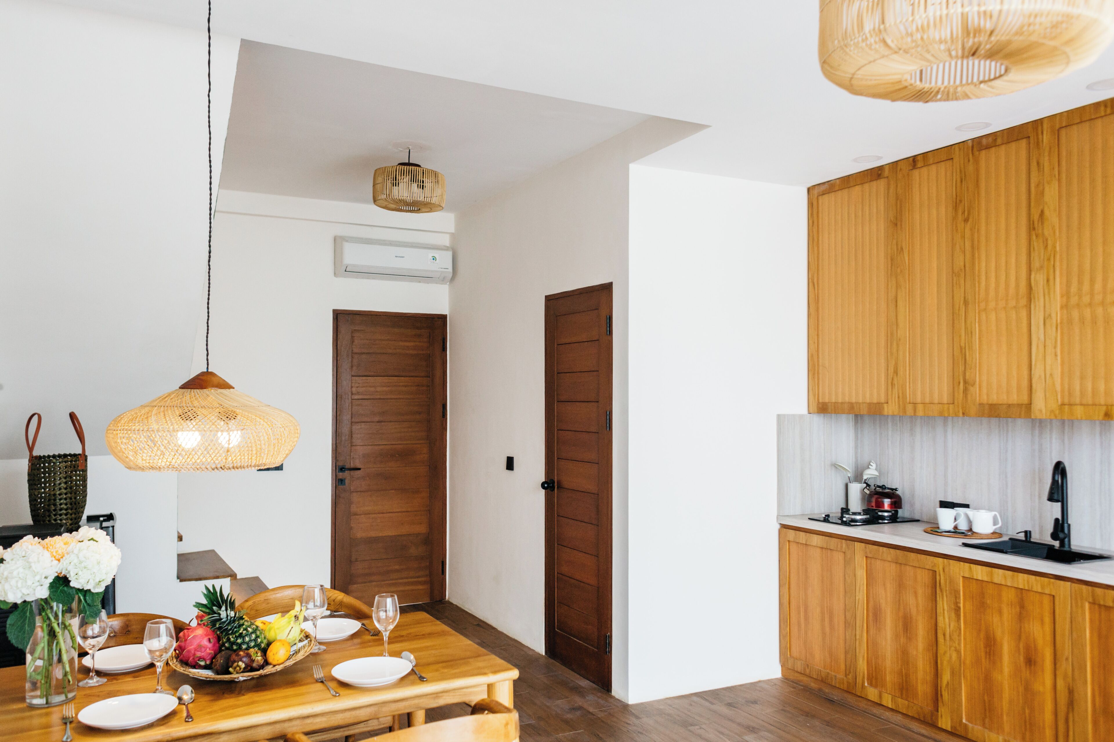 A dining area with a wooden table, chairs, and a hanging light fixture.