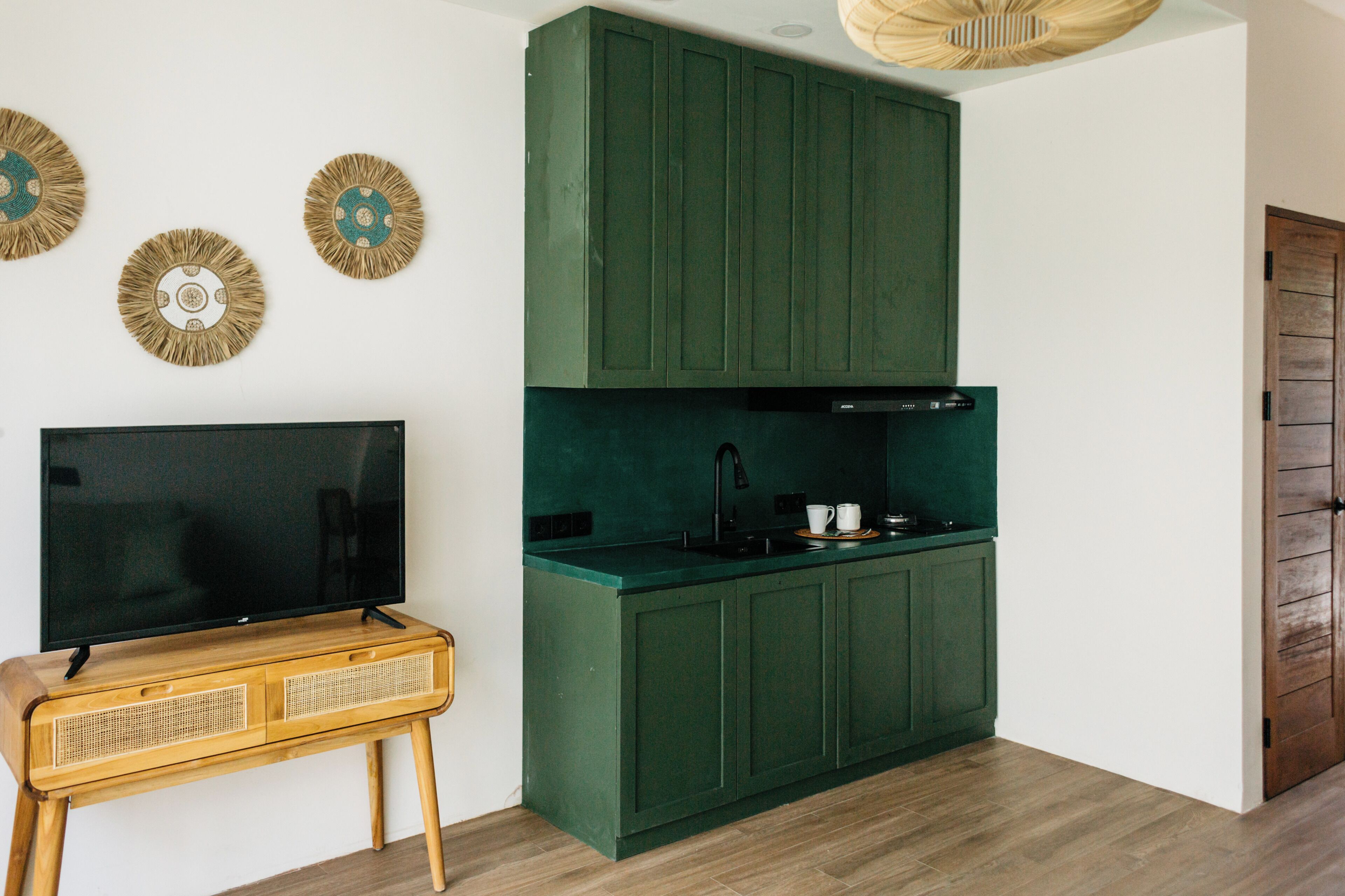 Eine kompakte Küche mit Flachbildfernseher, Holzschrank und Wanddekoration.
