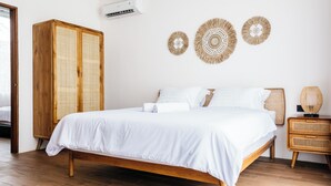 A bedroom with a wooden bed, a wardrobe, and three wall-mounted decorative items. - Santara by Prime Villas (Ubud)