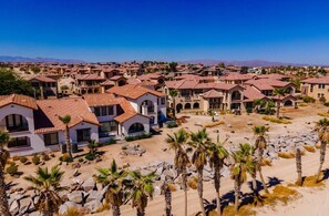 Zona residencial con varias casas que presentan techos de tejas rojas y paredes de estuco. Palmeras dispersas adornan el paisaje.