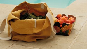 Zona junto a la piscina con un bolso amarillo y una cesta de frutas.