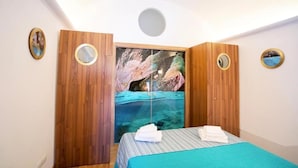 A bedroom with a bed, wooden wardrobe, and a large window with a view of a rocky landscape. - Grotta Verde Luxury Suite (Capri)