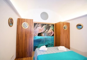 Ein Schlafzimmer mit Bett, Holzschrank und einem großen Fenster mit Blick auf eine felsige Landschaft.