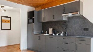Une cuisine moderne avec des armoires grises, une hotte de cuisinière en acier inoxydable et un plafond en bois.