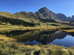 Eine bergige Landschaft mit einem stillen See, der die Umgebung spiegelt.