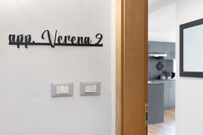 A wall with a nameplate reading 'Verena 2' and two light switches.