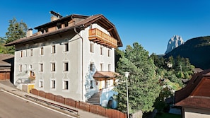 Un edificio de varios pisos con un balcón, una escalera y vistas a las montañas.
