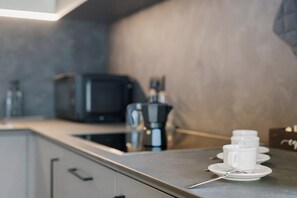 A kitchen counter with a coffee maker, a toaster, and a set of white cups and saucers. - Ferienwohnung 'Verena 2 – im Herzen der Dolomiten' (Urtijëi)