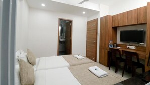Una camera d'albergo con due letti, una scrivania, un televisore e una ventola a soffitto.