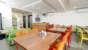 Un ristorante con diversi tavoli e sedie, un bancone e uno schermo televisivo.