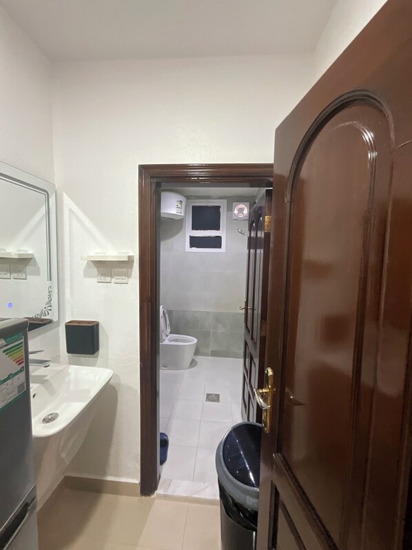 Casa de banho com sanita, lavatório e um contentor de lixo.