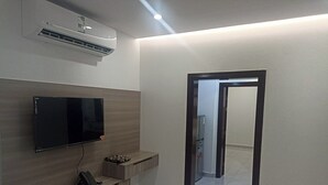 A modern interior with a flat-screen TV mounted on a wooden wall, a built-in bench, and a doorway leading to another room. - Al Baida Suites, Rosana Branch (Madinah)