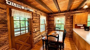 Ein rustikales Holzhaus-Interieur mit Esstisch, Stühlen, einer Küchenzeile und einem Schild mit der Aufschrift 'WILSON POINT'.