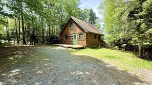 Eine Blockhütte mit Veranda, umgeben von dichtem Wald.