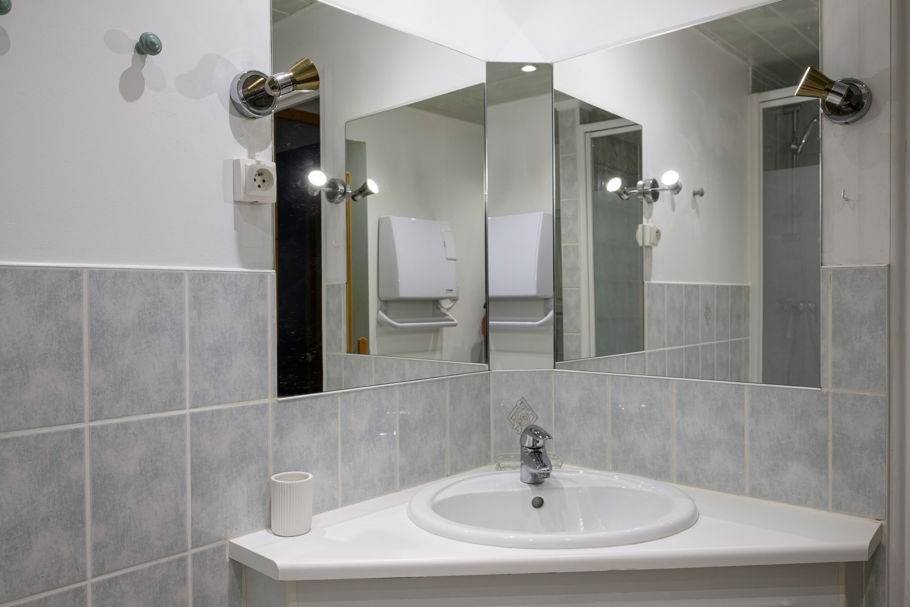 A bathroom with a white sink, mirror, and tiled walls.