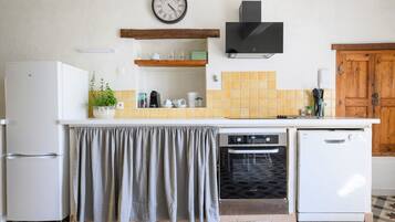 A kitchen with a refrigerator, oven, dishwasher, and a clock on the wall.