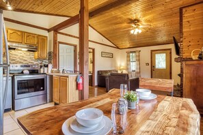 A spacious kitchen with wooden cabinets, a large dining table, and a ceiling fan. - Rivers Ridge & Guest House - New Listing (Sevierville)
