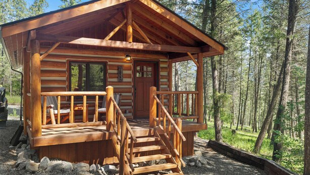 A log cabin with a wooden staircase, a porch, and a door.