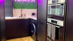 Eine moderne Küche mit Waschmaschine, Einbauofen und einer Neonreklame.