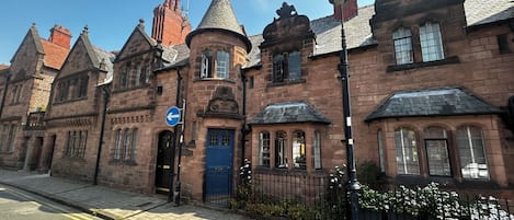 A historic building with a blue door, a pointed tower, and a blue directional sign.