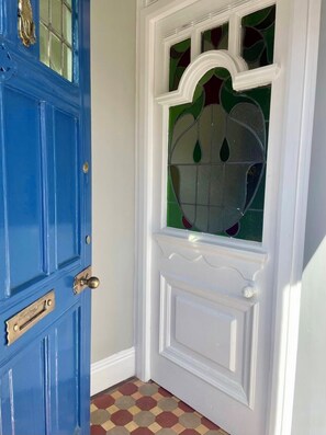 Eine blaue Tür mit weißem Zierrahmen und einem Fenster mit dekorativem Muster.