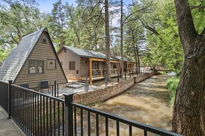 A log cabin with a porch and a small bridge over a stream. - Inviting Rustic Cabins with Outdoor Gathering Areas near Garden of the Gods in Colorado Springs, Colorado (Colorado Springs)