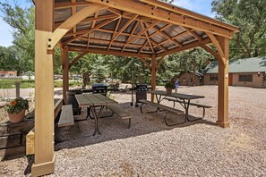 A wooden pavilion with picnic tables and barbecue grills. - Inviting Rustic Cabins with Outdoor Gathering Areas near Garden of the Gods in Colorado Springs, Colorado (Colorado Springs)