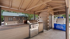 Eine Außenküche mit Grill, Herd und einem Kühlschrank mit der Aufschrift 'Arctic Glacier Premium Ice'.