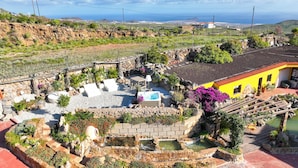 Un giardino con piscina, un muro in pietra e un edificio giallo.